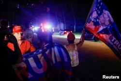Pristalice Donalda Trumpa stoje ispred njegove kuće u Mar-a-Lagu na Floridi nakon što je Trump rekao da su agenti FBI-a izvršili pretres njegove rezidencije.