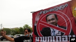 An anti-government protester takes a selfie beside a poster of Prime Minister Prayuth Chan-ocha in Bangkok, Aug. 24, 2022.