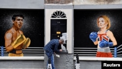 Seniman Ciaran Gallagher menyelesaikan mural buatannya yang menampilkan kandidat pemimpin Partai Konservatif Inggris Rishi Sunak dan Liz Truss, pada 17 Agustus 2022. Mural tersebut dibuat di pusat Kota Belfast, Irlandia Utara. (Foto: Reuters/Clodagh Kilcoyne)