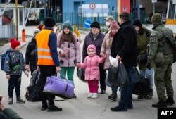 Slovak soldiers and volunteers help Ukrainian refugees after they crossed the border in Vysne Nemecke, eastern Slovakia, on February 26, 2022.