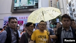 FILE - Pro-democracy activist Tam Tak-chi, center, is escorted away by police after confronting government supporters in Hong Kong, April 25, 2015.