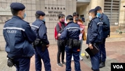 防疫二人限聚令下，社民连主席陈宝莹与成员余炜彬在西九龙裁判法院外结束请愿行动后，数名警员随即上前将他们包围，要求搜查随身物品 (美国之音/汤惠芸)
