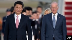 FILE - In this Sept. 24, 2015 file photo, Chinese President Xi Jinping and Vice President Joe Biden walk down the red carpet on the tarmac during an arrival ceremony in Andrews Air Force Base, Md.