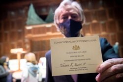 یک عضو کالج انتخاباتی از ایالت پنسیلوانیا رای نهایی شده این ایالت به نام جو بایدن را به دوربین عکاس خبرگزاری رویترز نشان می‌دهد.