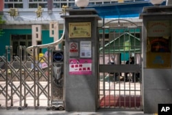 北京市朝阳区一所小学校的保安坐在紧闭的校门内。（2022年4月28日）