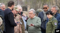 Generalni sekretar UN Antonio Gutereš razgovara sa lokalnim sveštenikom stojeći blizu masovne grobnice u Buči, u predgrađu Kijeva, 28. aprila 2022. 