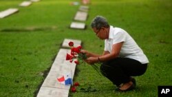 Una mujer coloca flores en la tumba de una persona que murió durante la invasión militar estadounidense de 1989 que derrocó al dictador panameño Manuel Noriega, en el 30 aniversario de la invasión en Ciudad de Panamá, el viernes 20 de diciembre de 2019.