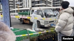 身穿防護服的警察站在運送綠色鐵絲圍欄的汽車旁。 （2022年4月15日）