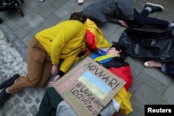 Climate activists perform at a protest in front of the German Embassy on Earth Day to call for an immediate embargo on Russian oil and gas, in Brussels, Belgium, April 22, 2022. (REUTERS/Johanna Geron)