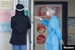 A health care worker wearing personal protective equipment (PPE) talks to a patient at a clinic designated to treat patients for COVID-19, in Hong Kong, China, March 7, 2022.