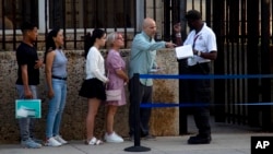 People stand in line outside the U.S. embassy on the day of its reopening for visa and consular services in Havana, Cuba, Jan. 4, 2023. (AP Photo/Ismael Francisco)