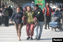 A family member of a victim of the aircraft that crashed in Pokhara is escorted as she mourns at the airport in Kathmandu, Nepal, Jan. 15, 2023.