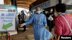 一名旅客在港珠澳大橋外與一名身穿防護服的工作人員交談。（2022年12月23日）