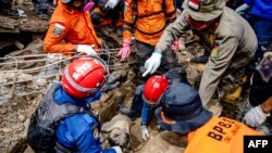 Tim SAR memindahkan puing-puing dari tubuh bocah berusia tujuh tahun Ashika Nur Fauziah, yang ditemukan tewas di bawah puing-puing di desa Cugenang, di Cianjur, pada 25 November 2022. ( Mas Agung Wilis/AFP)