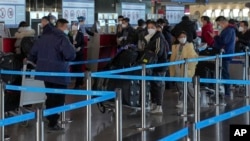 Travelers line up at the international flight check in counter at the Beijing Capital International Airport in Beijing, Dec. 29, 2022.