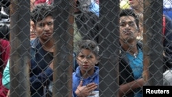 Members of a migrant caravan from Central America and their supporters look through the U.S.-Mexico border wall at Border Field State Park before making an asylum request, in San Diego, California, U.S. April 29, 2018. REUTERS/Lucy Nicholson