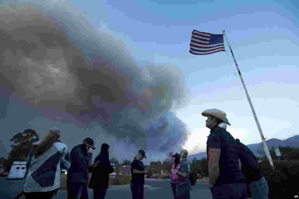 A group of horse rescuers stages in a parking lot as smoke from the Thomas fire billows over Ojai, California, Dec. 7, 2017. The volunteers, who met through a Facebook group, estimated that they have evacuated more than 100 horses from the fire.