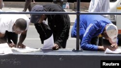 FILE - izizalwane zakwele Zimbabwe ezihlala kwele South Africa zilungisa amaphepha atshiyeneyo. (AP)