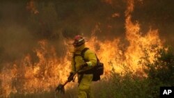 Un bombero de Cal Fire en Mendocino camina junto a una línea de contención mientras un incendio forestal avanza en Lakeport, California, el lunes, 30 de julio de 2018.