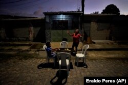 Quiteria Maria da Silva, with her grandson, Luri Andriel, calls up to her family. Da Silva is the last resident on her street, March 6, 2022. (AP Photo/Eraldo Peres)