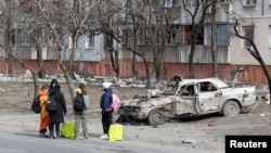 Refugees gather in a street as they leave the besieged southern port of Mariupol, Ukraine, March 20, 2022. (REUTERS/Alexander Ermochenko)