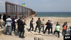 Local residents carry bags filled with sand as they build a barricade for a checkpoint in Odessa on March 25, 2022, amid the Russian invasion of Ukraine.