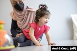 In this photo provided by the Children's Hospital of Eastern Ontario, Ayla Bashir sits with her mother, Sobia Qureshi, during a physical therapy assessment for Ayla at CHEO in Ottawa on Aug. 23, 2022. (André Coutu/CHEO via AP)