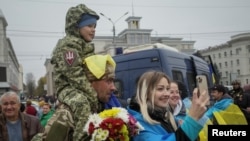 Local residents take a photo with Ukrainian serviceman as they celebrate after Russia's retreat from Kherson city, in downtown Kherson, Ukraine, Nov. 12, 2022. 