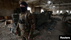 A Ukrainian soldier stands next to cases of ammunition abandoned by retreating Russian forces in the village of Blahodatne, in Ukraine's Kherson region, Nov. 11, 2022.