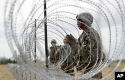FILE - Members of a U.S Army engineering brigade place concertina wire around an encampment near the U.S.-Mexico international bridge, Nov. 4, 2018, in Donna, Texas.