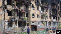 A man walks past a destroyed apartment building in Mariupol, in territory under the government of the Donetsk People's Republic, eastern Ukraine, May 4, 2022.