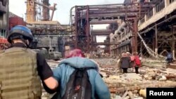 Azov regiment members walk with civilians during UN-led evacuations from the sprawling Azovstal steel plant, after nearly two months of siege warfare on the city by Russia during its invasion, in Mariupol, Ukraine in this still image from handout video released May 1, 2022.