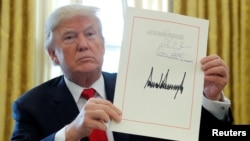 ARCHIVO - Donald Trump muestra su firma después de convertir en ley un proyecto de ley de impuestos en la Casa Blanca en Washington, el 22 de diciembre de 2017.