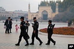FILE - Uighur security personnel patrol near the Id Kah Mosque in Kashgar in western China's Xinjiang region, Nov. 4, 2017.
