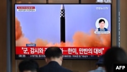 People watch a television screen showing a news broadcast with file footage of a North Korean missile test, at a railway station in Seoul on May 25, 2022.