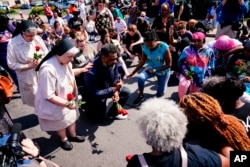 La gente reza fuera de la escena de un tiroteo en un supermercado en Buffalo, N.Y., 15 de mayo de 2022.