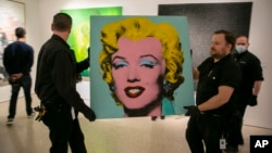 The 1964 silk-screen image, "Shot Sage Blue Marilyn," by Andy Warhol is carried in Christie's showroom in New York, Sunday, May 8, 2022. The image sold for $195 million, Monday, May 9. (AP Photo/Ted Shaffrey, File)