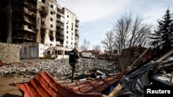 俄军战争罪调查小组一名成员站在基辅地区一座被俄军炮火摧毁的大楼前打电话。（2022年4月7日）