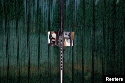 一名女子从因防疫被锁住的住宅小区门里向外张望。（2022年5月24日）