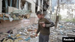 FILE - A local man walks on debris of a residential building damaged by a military strike, as Russia's attack on Ukraine continues, in Sievierodonetsk, Luhansk region, Ukraine. April 16, 2022. 