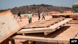 FILE - Employees of the Jiuxing Chinese mining company walk on the mining site Oct. 7, 2016, in Soamahamanina, Madagascar.