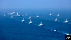 Liaoning aircraft carrier is accompanied by navy frigates and submarines conducting an exercises in the South China Sea. 