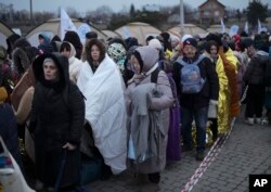 File photo shows refugees waitingg in a crowd for transportation after fleeing from the Ukraine and arriving at the border crossing in Medyka, Poland, Monday, March 7, 2022.