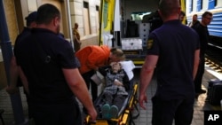 A woman fleeing from shelling waits in a stretcher to board an evacuation train at the train station, in Pokrovsk, eastern Ukraine, eastern Ukraine, May 27, 2022.