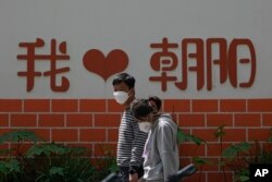 北京朝陽區兩個帶著口罩的居民去排隊做新冠核酸檢測。（2022年5月11日）