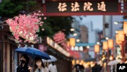 FILE - People walk through a shopping street along the famed Sensoji temple in the Asakusa neighborhood in Tokyo, April 29, 2021.