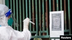 上海一名醫務人員從一個固定新冠核酸採樣點裡給市民進行檢測。（2022年5月5日）