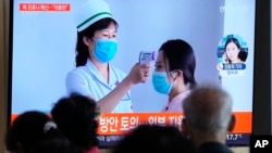 Ljudi gledaju TV program i prilog u emisiji vesti o izbijanju pandemije Kovida 19 u Severnoj Koreji, na železničkoj stanici u Seulu, Južna Koreja, 14. maja 2022.