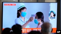 People watch a TV screen showing a news report about the COVID-19 outbreak in North Korea, at a train station in Seoul, South Korea, May 14, 2022. 