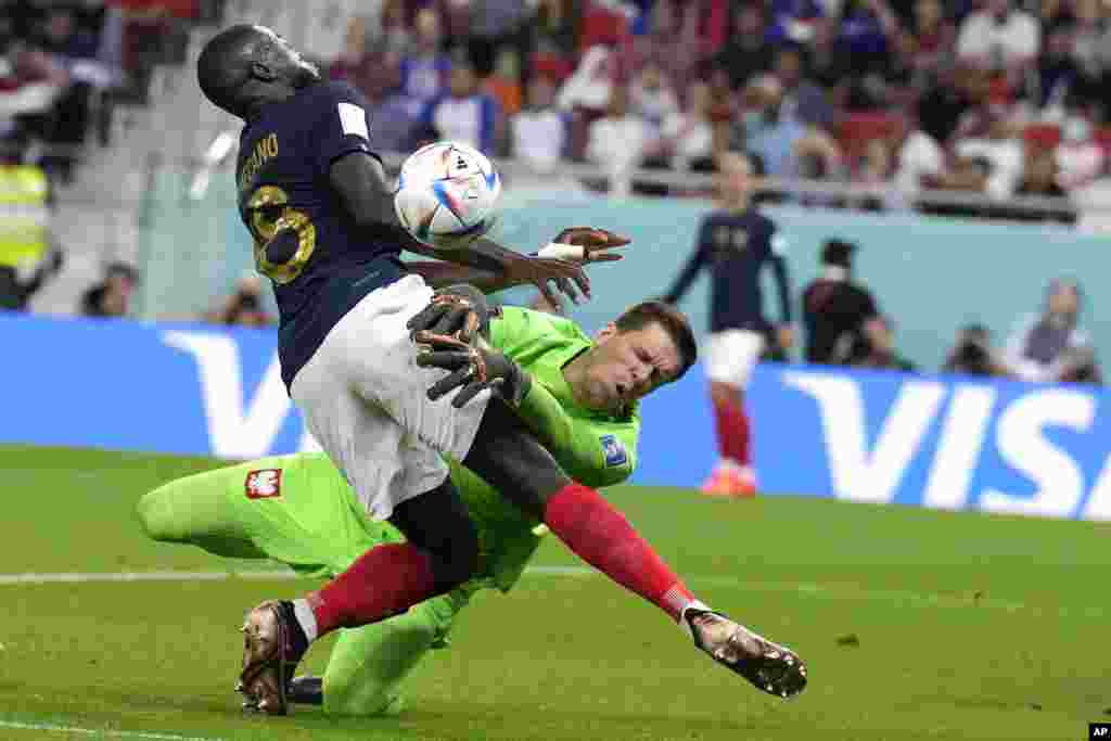 France's Dayot Upamecano, left, and Poland's goalkeeper Wojciech Szczesny, right, collide during the World Cup round of 16 soccer match between France and Poland, at the Al Thumama Stadium in Doha, Qatar.